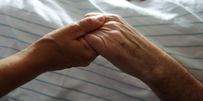 Junge Hand hält alte hand am Krankenhausbett
