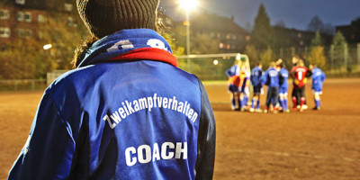 Zweikampfverhalten e.V.: Coach mit blauer Trainingsjacke und dem Schriftzug 