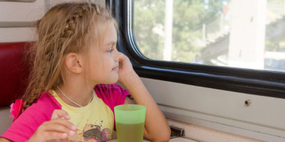 Alleinreisende Kinder: Fürsorgepflicht und andere Regeln. Ein kleines Mädchen sitzt im Zug und guckt aus dem Fenster.