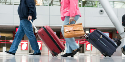 Handgepäck im Flugzeug: So viel dürfen Sie mitnehmen. Menschen ziehen ihre Koffer durch das Terminals eines Flugzeugs.