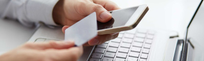 Männerhand mit Kreditkarte beim Online-Shopping am Laptop