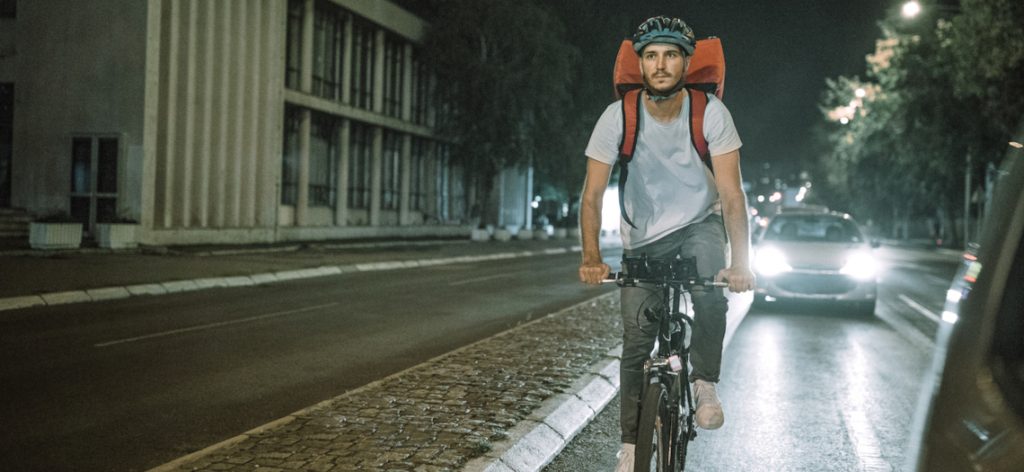 Man riding bicycle for home delivery of food in city at night