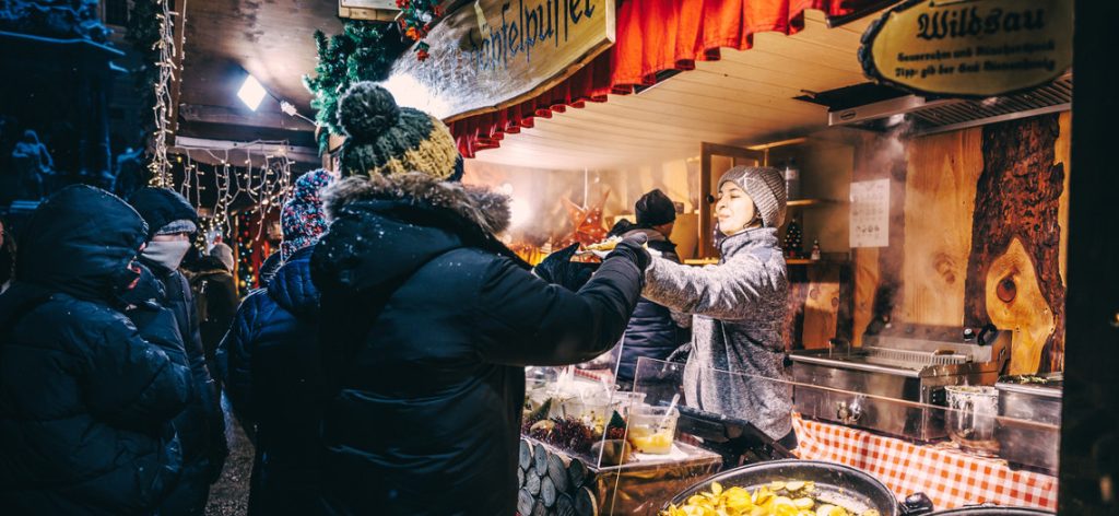 Frau gibt auf einem Wintermarkt Gebäck aus