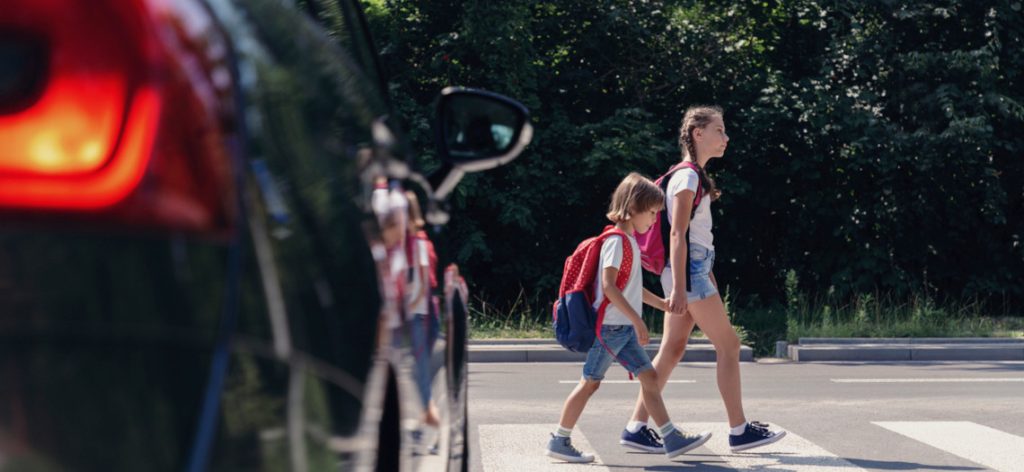 Zwei Kinder überqueren auf dem Schulweg einen Zebrastreifen