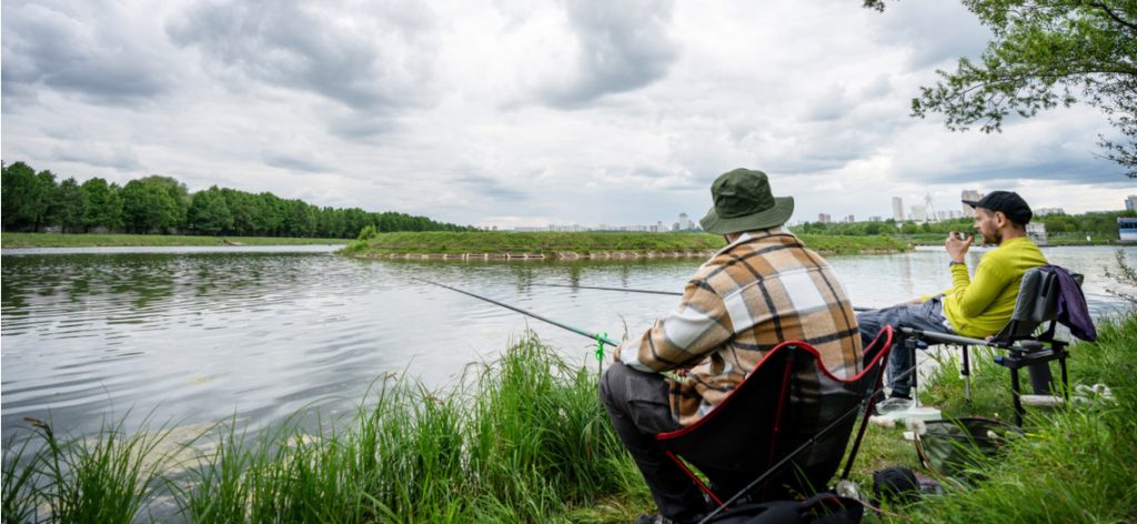 Zwei Männer sitzen an einem Fluss und angeln